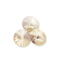 Three round champagne-colored faceted crystal gemstones on white background