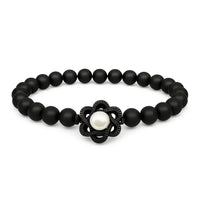 Black beaded bracelet with a central pearl and black flower-shaped clasp on a white background