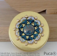 Decorative round compact with gold and gemstone design on a wooden surface, featuring Puca brand.