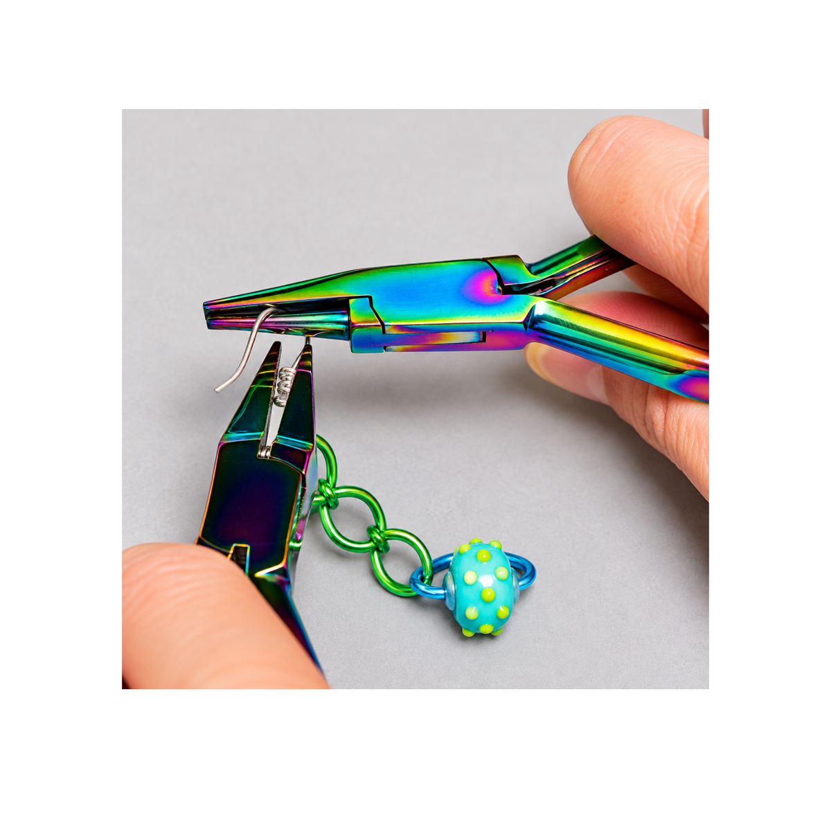 Chroma Series Round Concave Pliers being used to form a wire loop with colourful chain links and a turquoise bead