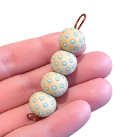 Polka dot beads on a string held between fingers against a white background
