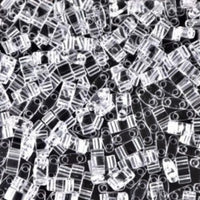 Clear rectangular plastic beads with two holes scattered on a black surface