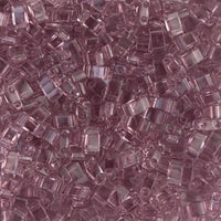 Close-up of translucent pink glass seed beads with a square shape and two holes, perfect for jewelry making