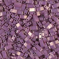 Close-up of numerous small, rectangular purple beads with two holes each, for jewelry making