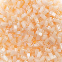 Close-up of translucent peach plastic craft beads with two holes, scattered densely
