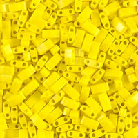 Close-up of numerous small yellow rectangular plastic beads with two holes for crafting