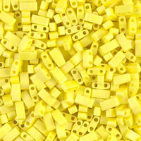 Close-up of yellow rectangular beads with two holes, scattered densely