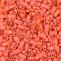 Close-up of numerous rectangular orange plastic beads with two holes, scattered randomly