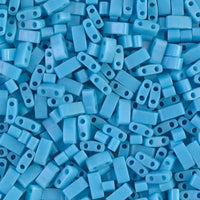 Close-up of small blue two-hole beads scattered on a surface, ideal for jewelry making