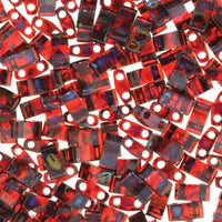 Close-up of glossy red rectangular beads with two holes, scattered on a white surface