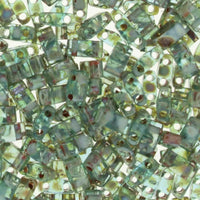 Transparent green glass seed beads with two holes, scattered on a white background