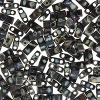 Close-up of black rectangular two-hole Czech glass beads with light spots, beadwork supplies