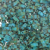 Close-up of turquoise blue Czech glass rectangular beads with two holes, brown patina finish