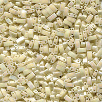 Close-up of multiple small rectangular beige beads with two holes, used for jewelry making