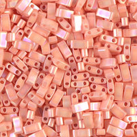 Close-up of small peach pink rectangular two-hole beads with a glossy finish