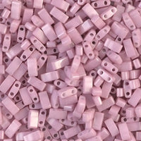 Close-up of light pink two-hole rectangular beads scattered densely