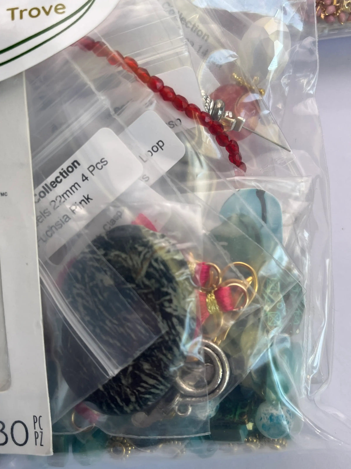 Assorted jewelry items in a clear plastic container with labels.