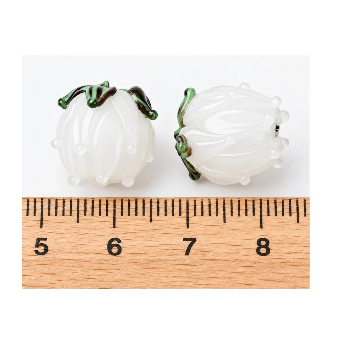 Handmade white lampwork tulip flower beads shown beside ruler for size reference