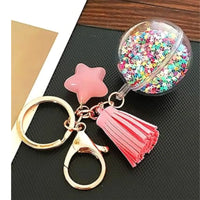 Keychain with star, tassel, and glittery ball charm on a dark surface