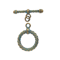 Decorative metal toggle with a patina and gold twisted design on a white background