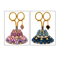 Two decorative beaded scissor holders in purple and navy blue colourways, displaying gold-handled scissors and dangling charms as Porte Bonheur pattern inspiration.