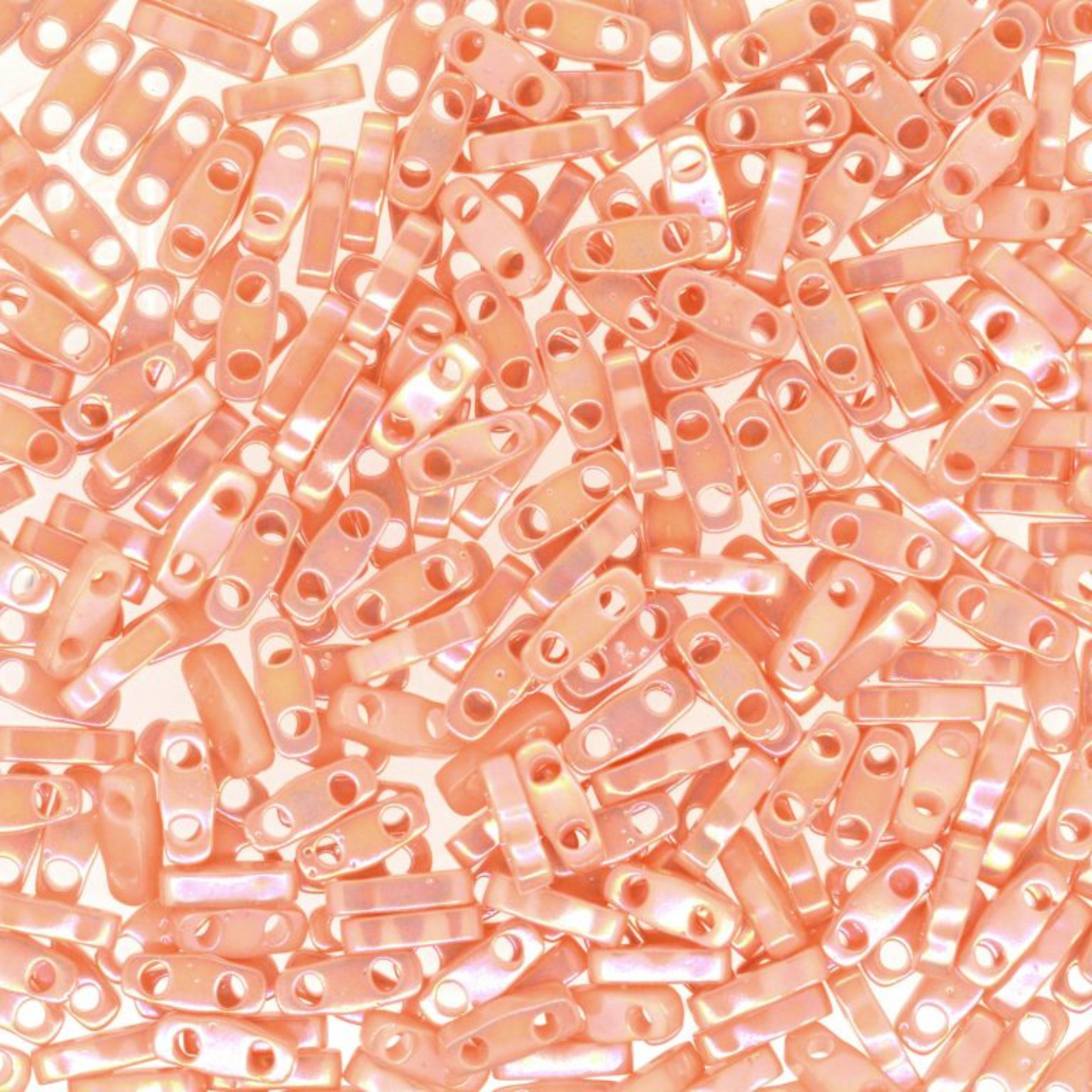 Close-up of pinkish-beige cylindrical beads with holes on a white background