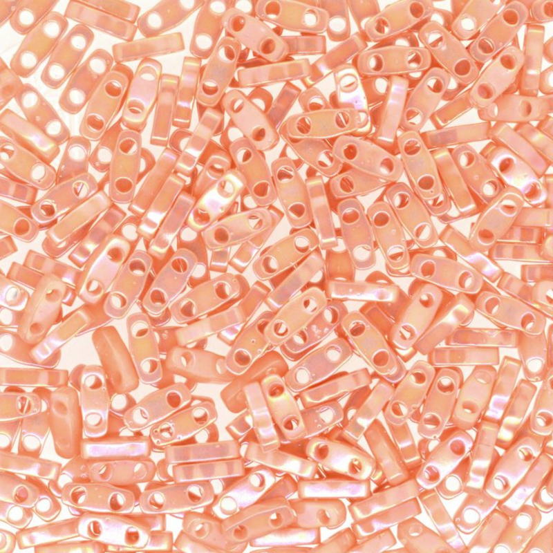 Close-up of pinkish-beige cylindrical beads with holes on a white background