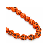 A strand of orange-red skull-shaped beads with black veining and dark eye sockets, arranged in a curved line on a plain white background.