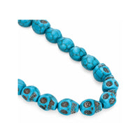 A strand of turquoise-colored round beads with dark matrix veining and silver-toned metal accents, photographed on a plain white background.