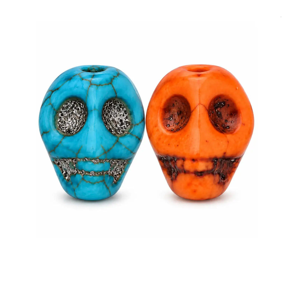 Two decorative skull-shaped beads on a white background, one in bright turquoise blue with dark veining and the other in bright orange with dark marbling.
