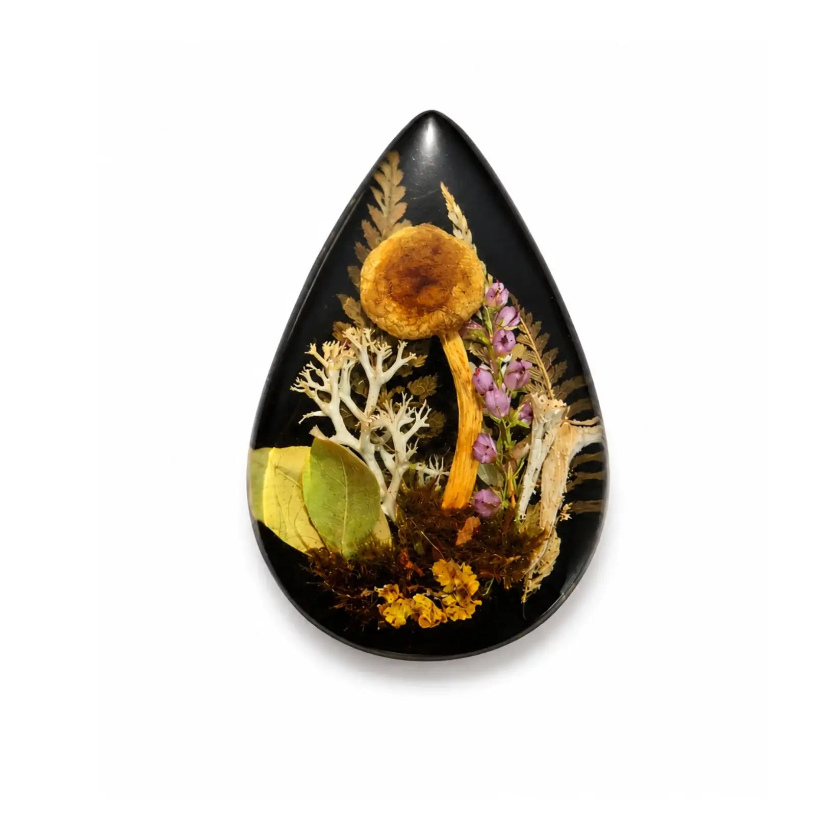 Teardrop-shaped black pendant with pressed flowers and leaves on a white background