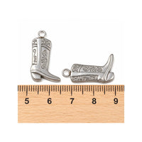 Stainless steel cowboy boot charms shown beside a ruler for size reference