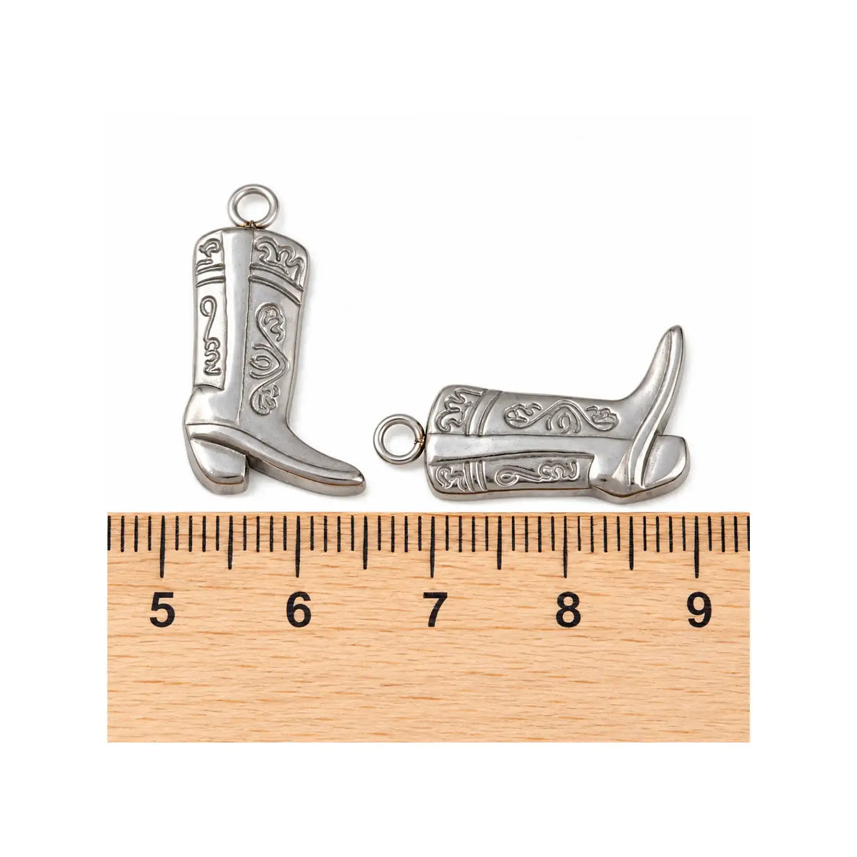 Stainless steel cowboy boot charms shown beside a ruler for size reference